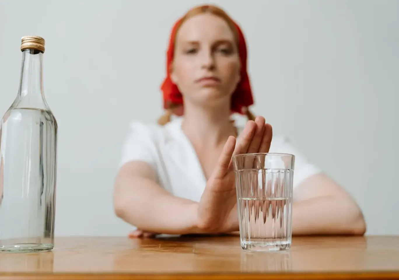 Leczenie alkoholizmu Łomża, kompleksowy program farmakoterapii, wszywki i psychoterapii: kobieta odsuwa butelkę i sięga po wodę